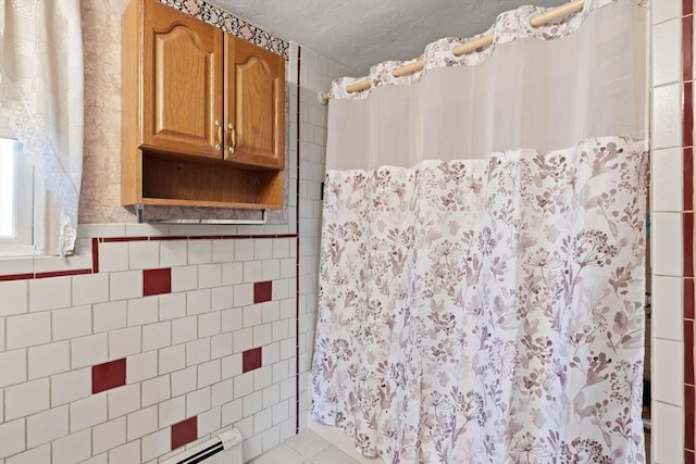 bathroom with tile patterned flooring, baseboard heating, and tile walls