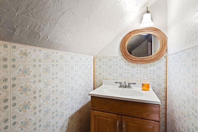 bathroom with vanity, tile walls, and lofted ceiling