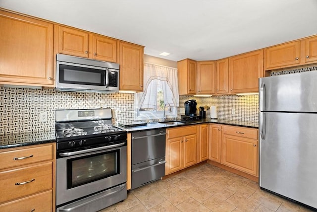 kitchen featuring backsplash, dark stone countertops, sink, and appliances with stainless steel finishes