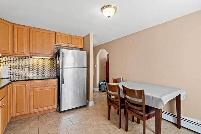 kitchen with a baseboard radiator, stainless steel refrigerator, and tasteful backsplash