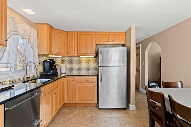 kitchen featuring backsplash, dark stone countertops, sink, and appliances with stainless steel finishes