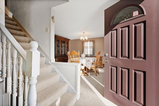 carpeted foyer with a notable chandelier