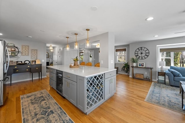 kitchen with plenty of natural light, gray cabinets, light wood finished floors, light countertops, and wine cooler