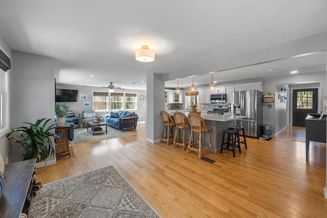 living area with recessed lighting, light wood-style flooring, a ceiling fan, and baseboards