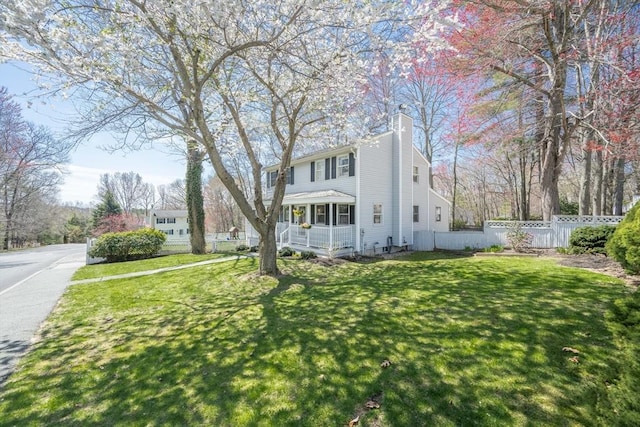 exterior space with fence, a front lawn, a chimney, and a porch