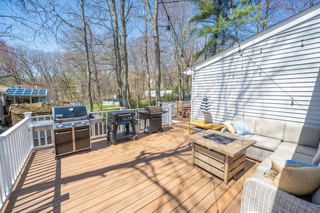 wooden terrace with outdoor dining area, a grill, and an outdoor living space with a fire pit