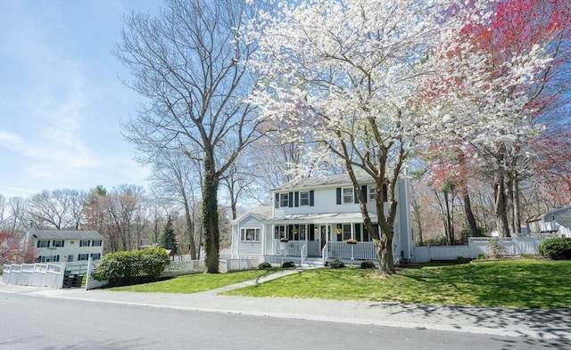 view of front of house with a porch, fence, and a front yard