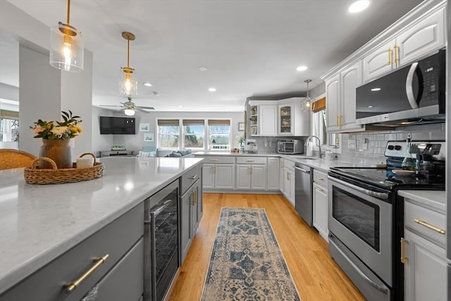 kitchen featuring white cabinets, beverage cooler, decorative light fixtures, and stainless steel appliances