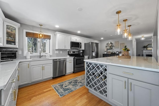 kitchen with stainless steel appliances, a sink, decorative light fixtures, decorative backsplash, and white cabinetry