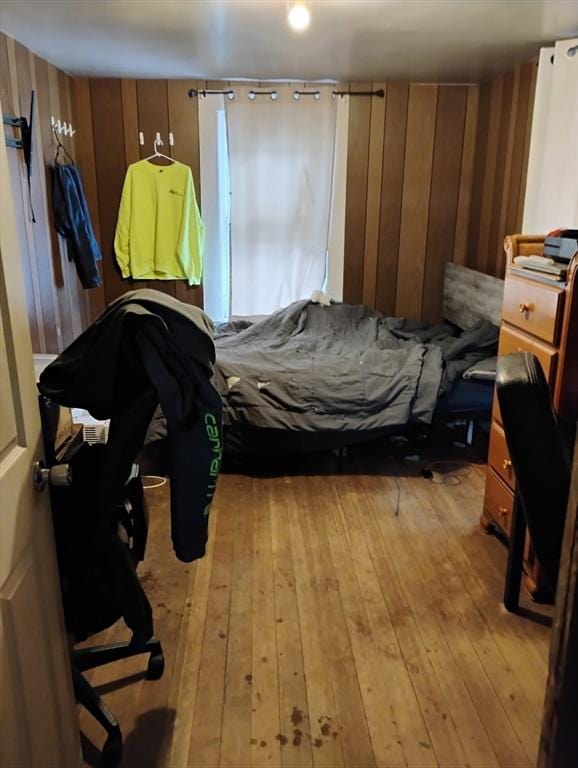 bedroom with wooden walls and light hardwood / wood-style floors