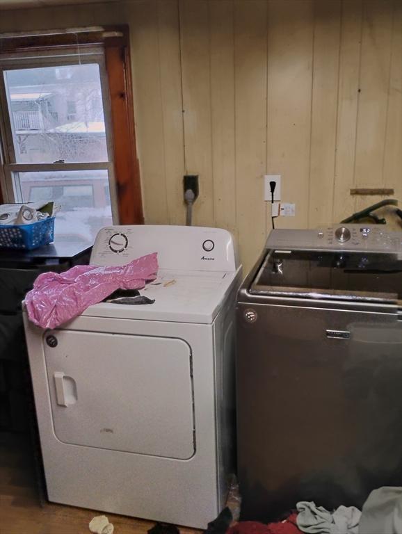 washroom with hardwood / wood-style flooring, washer and clothes dryer, and wood walls