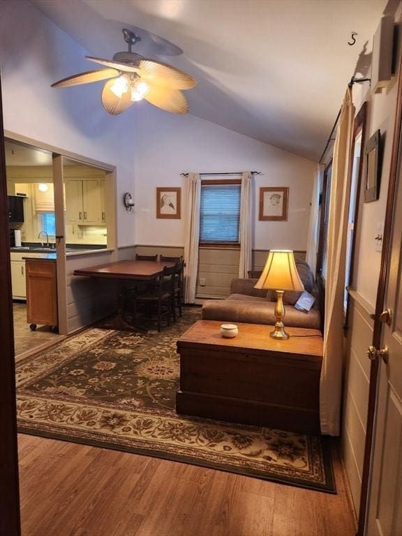 living area with wood-type flooring, vaulted ceiling, and ceiling fan