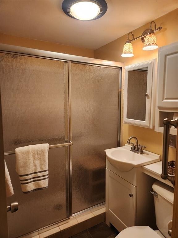 bathroom featuring tile patterned flooring, vanity, toilet, and walk in shower