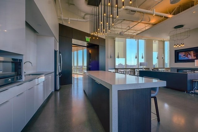 kitchen featuring a spacious island, sink, hanging light fixtures, and stainless steel appliances