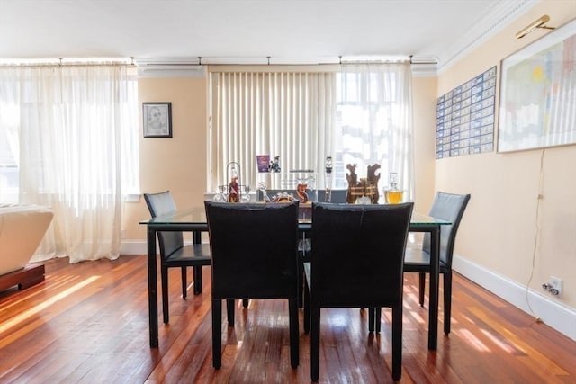 dining room featuring crown molding, baseboards, and hardwood / wood-style flooring
