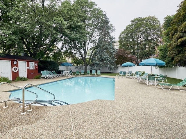 community pool with a patio and fence
