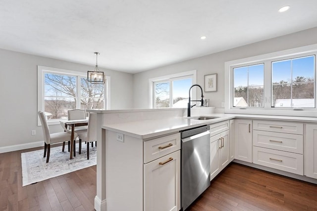 kitchen featuring pendant lighting, sink, dishwasher, white cabinetry, and dark hardwood / wood-style flooring