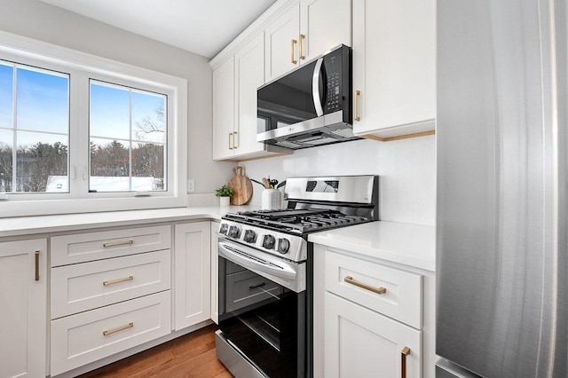 kitchen with white cabinetry, wood-type flooring, and appliances with stainless steel finishes