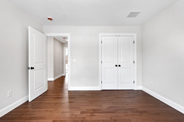 unfurnished bedroom with dark hardwood / wood-style floors and a closet