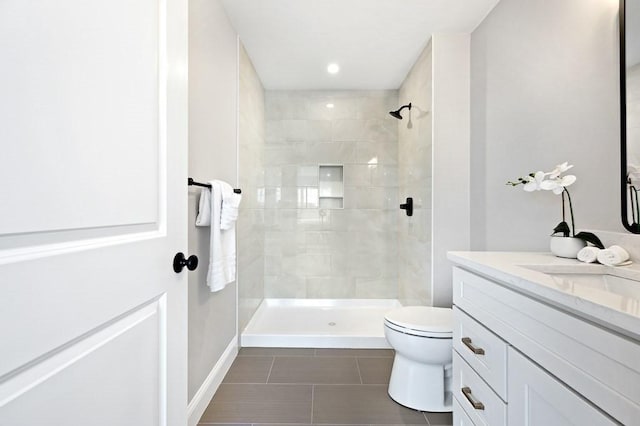 bathroom with tiled shower, vanity, toilet, and tile patterned flooring