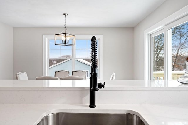 room details featuring pendant lighting, sink, light stone counters, and a chandelier