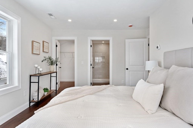 bedroom featuring a closet, dark hardwood / wood-style flooring, multiple windows, and a spacious closet