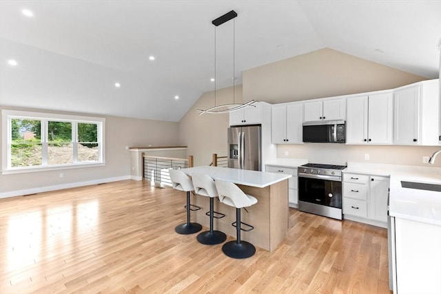 41 Kent St, Brockton, MA 02302 - kitchen featuring stainless steel appliances, vaulted ceiling, a kitchen island, a breakfast bar, and light countertops