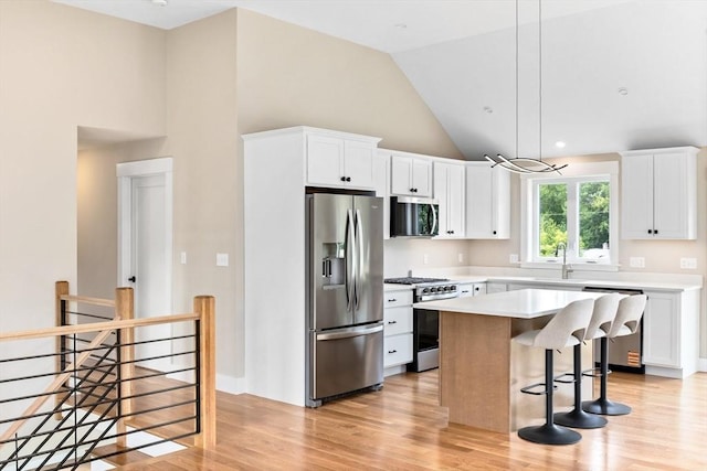 41 Kent St, Brockton, MA 02302 - kitchen featuring appliances with stainless steel finishes, a center island, light countertops, a kitchen breakfast bar, and light wood-style flooring