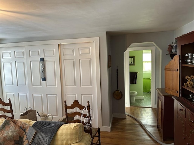 bedroom with dark wood-type flooring, connected bathroom, and a closet