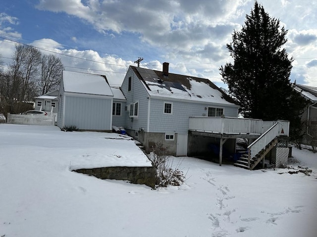 snow covered house featuring a wooden deck