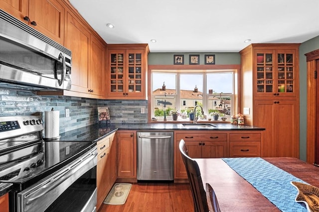 11 Raymond Rd Unit 2, Salem, MA 01970 - kitchen featuring appliances with stainless steel finishes, dark countertops, glass insert cabinets, wood finished floors, and decorative backsplash