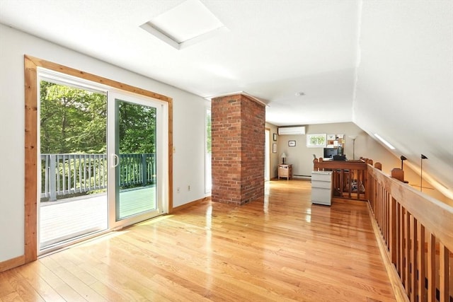 237 Shutesbury Rd, Amherst, MA 01002 - unfurnished living room with a wall mounted AC, light wood-type flooring, a baseboard heating unit, lofted ceiling, and baseboards