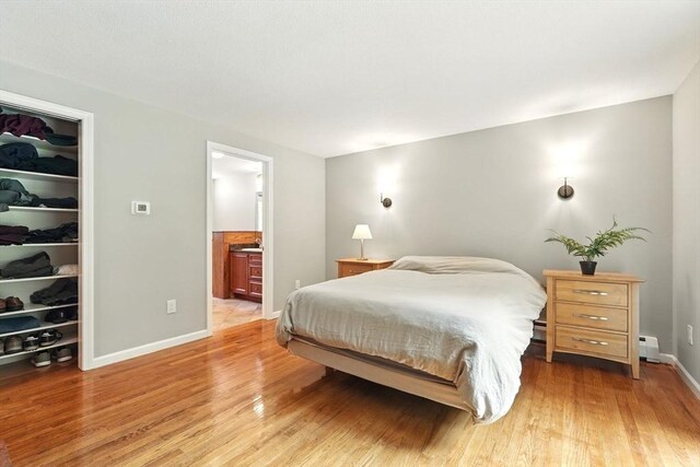 237 Shutesbury Rd, Amherst, MA 01002 - bedroom featuring light wood-style floors, a closet, a baseboard radiator, a walk in closet, and baseboards