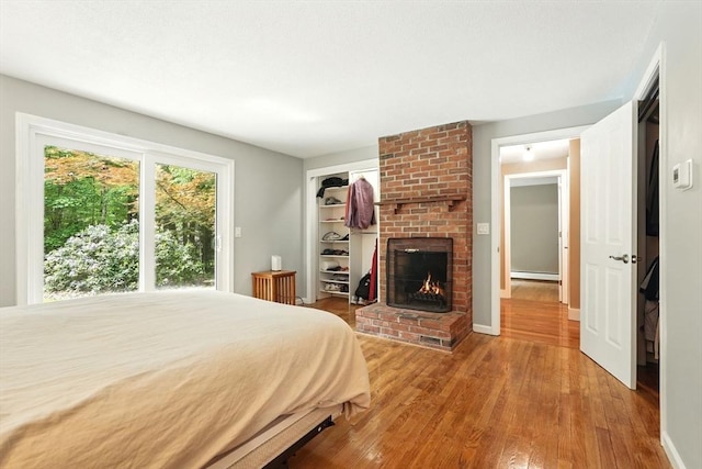 237 Shutesbury Rd, Amherst, MA 01002 - bedroom with wood-type flooring, baseboard heating, a brick fireplace, baseboards, and a closet