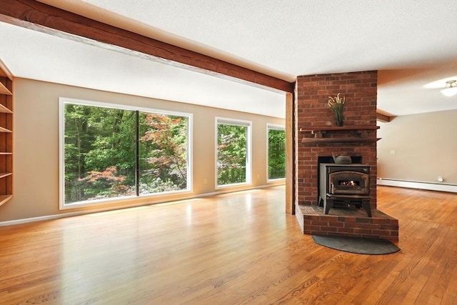 237 Shutesbury Rd, Amherst, MA 01002 - unfurnished living room featuring baseboard heating, a wood stove, wood finished floors, and baseboards