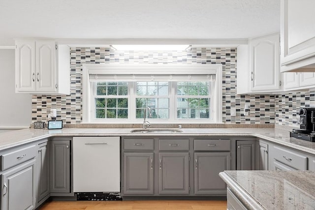 kitchen featuring gray cabinetry, a sink, dishwasher, and backsplash