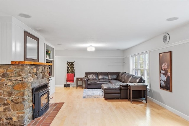 living room featuring wood finished floors, a wood stove, and baseboards