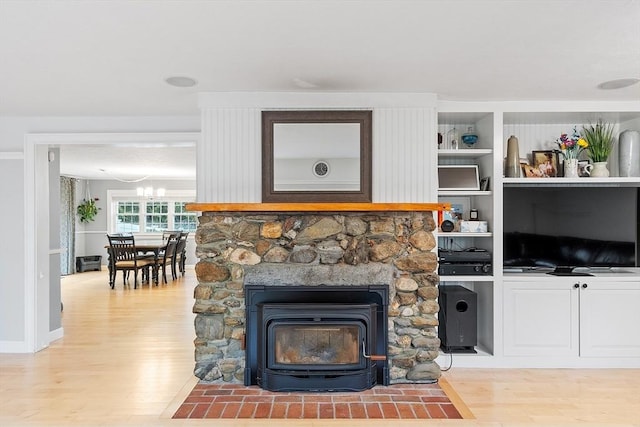 living room with light wood-type flooring, a wood stove, and a chandelier