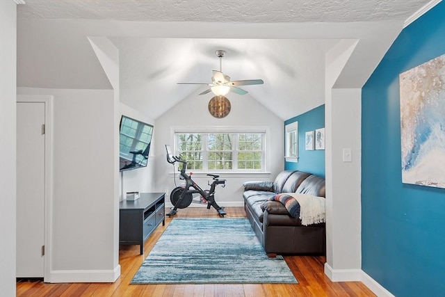 living area with a ceiling fan, light wood-type flooring, baseboards, and lofted ceiling