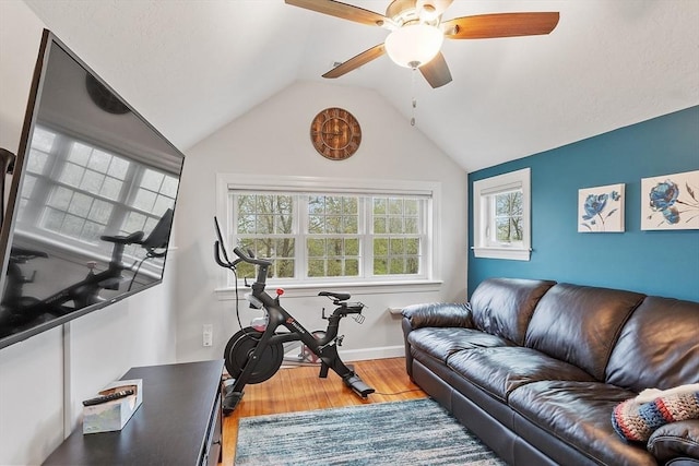 exercise area with ceiling fan, wood finished floors, vaulted ceiling, and baseboards