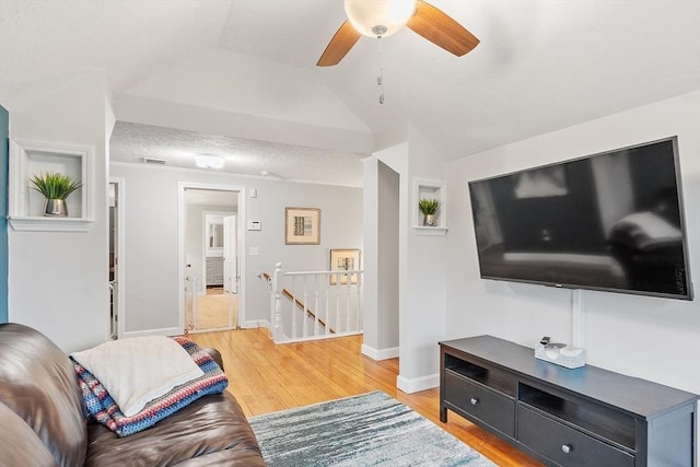 living area with light wood finished floors, a ceiling fan, baseboards, and vaulted ceiling