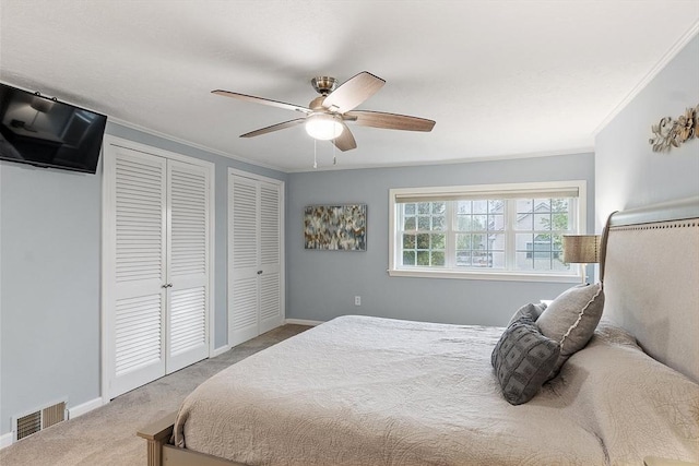 bedroom with multiple closets, carpet floors, crown molding, a ceiling fan, and baseboards