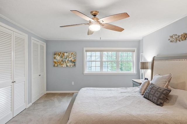 bedroom featuring carpet floors, two closets, ornamental molding, baseboards, and a ceiling fan