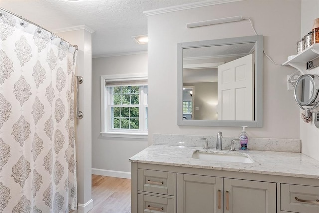full bath featuring crown molding, wood finished floors, vanity, baseboards, and a textured ceiling