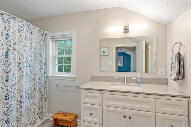 bathroom featuring a textured ceiling, vaulted ceiling, vanity, a shower with curtain, and baseboards