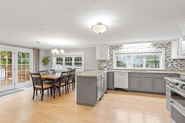 kitchen with gray cabinets, white dishwasher, a textured ceiling, backsplash, and light wood-style floors