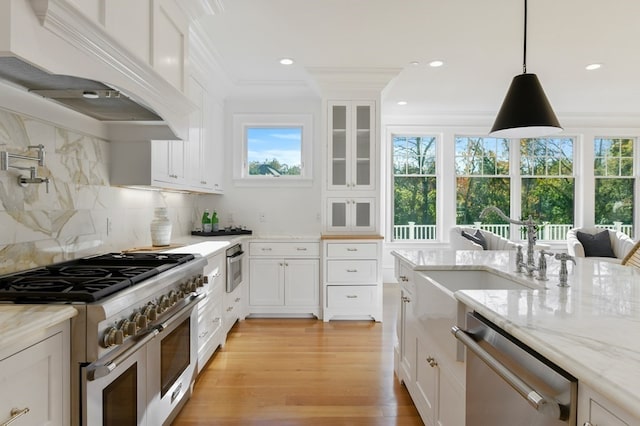 kitchen with tasteful backsplash, appliances with stainless steel finishes, a wealth of natural light, white cabinets, and custom range hood