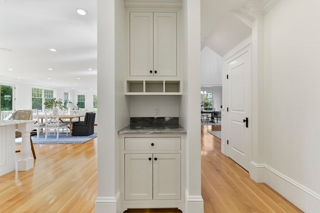 bar with light wood-type flooring, plenty of natural light, and white cabinetry