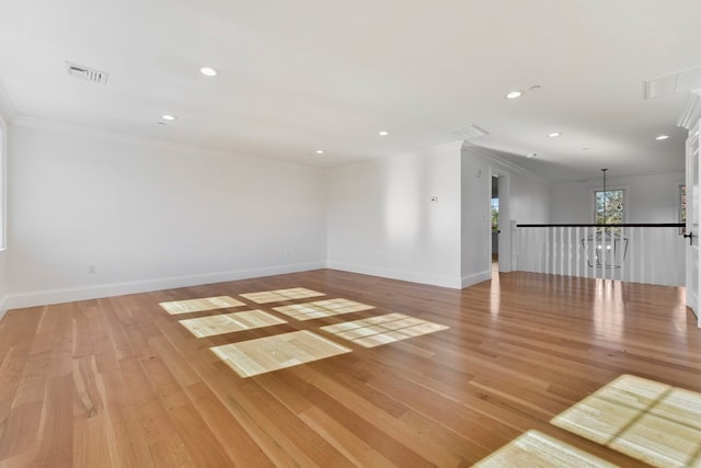 spare room featuring light wood-type flooring and crown molding