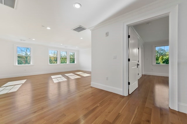 unfurnished room featuring light wood-type flooring, plenty of natural light, and crown molding